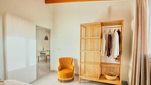 Et værelse med en stor garderobe, en rund lænestol og et lille bord med stole.