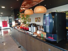 Una estación de café con una máquina de café, varios recipientes y un extintor rojo.