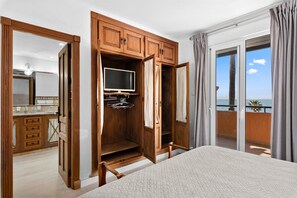 Een slaapkamer met een groot bed, een houten garderobe, een televisie en een balkon met uitzicht.