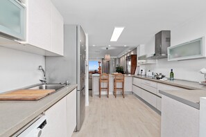 Een moderne keuken met een centraal eiland, roestvrijstalen apparatuur en uitzicht op de woonruimte.