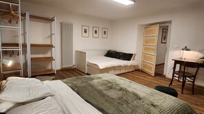 Een slaapkamer met een bed, een bureau met stoel, een kledingkast en een radiator.