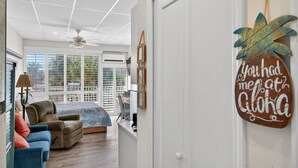 A room with a bed, two sofas, a ceiling fan, and a door with a leaf-shaped decoration. - Amazing Studio on Intracoastal Water Just Across from the Beach (Indian Shores)
