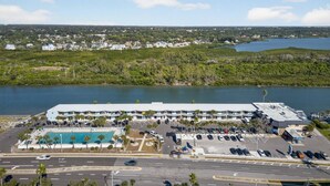 A large hotel with a swimming pool, parking lot, and a view of a lake. - Amazing Studio on Intracoastal Water Just Across from the Beach (Indian Shores)