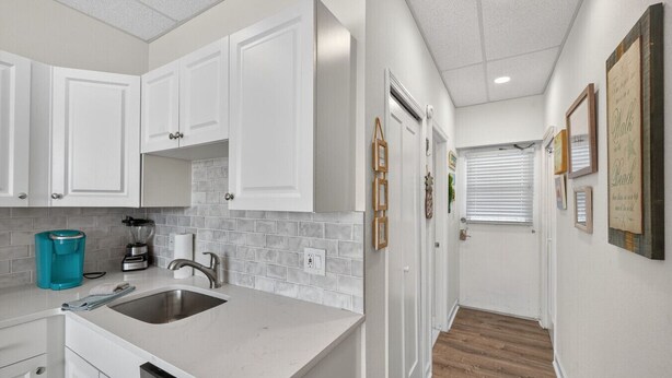 A modern kitchen with white cabinets, a stainless steel sink, and a countertop with a blender and coffee maker. - Amazing Studio on Intracoastal Water Just Across from the Beach (Indian Shores)