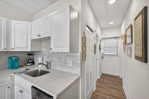 A modern kitchen with white cabinets, a stainless steel sink, and a countertop with a blender and coffee maker. - Amazing Studio on Intracoastal Water Just Across from the Beach (Indian Shores)