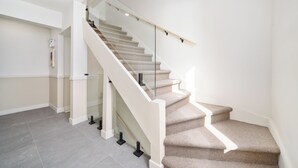 A modern staircase with glass railings and a beige carpet. - MTL Central Stay Apartments (Montréal)