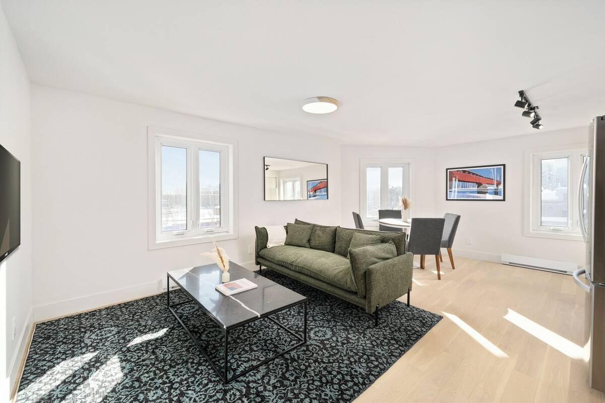 A modern living room with a sofa, coffee table, and dining area.