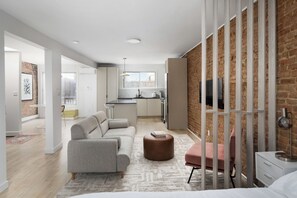 A modern apartment with a living area, kitchen, and a brick wall. - MTL Central Stay Apartments (Montréal)