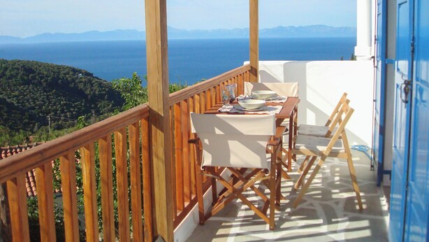 A balcony with a table set for two, overlooking a mountainous landscape and the sea. - Asteri Living (Alonissos)