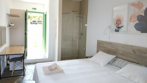 A hotel room with a bed, a desk, a shower, and a door leading outside. - Asteri Living (Alonissos)