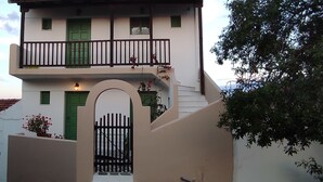A two-story building with a balcony, a green door, and a gate. - Asteri Living (Alonissos)