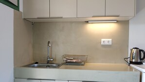 A compact kitchen with a sink, a kettle, and a dish rack. - Asteri Living (Alonissos)
