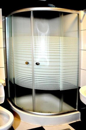 Un receveur de douche d’angle avec une porte en verre dépoli et un socle blanc.