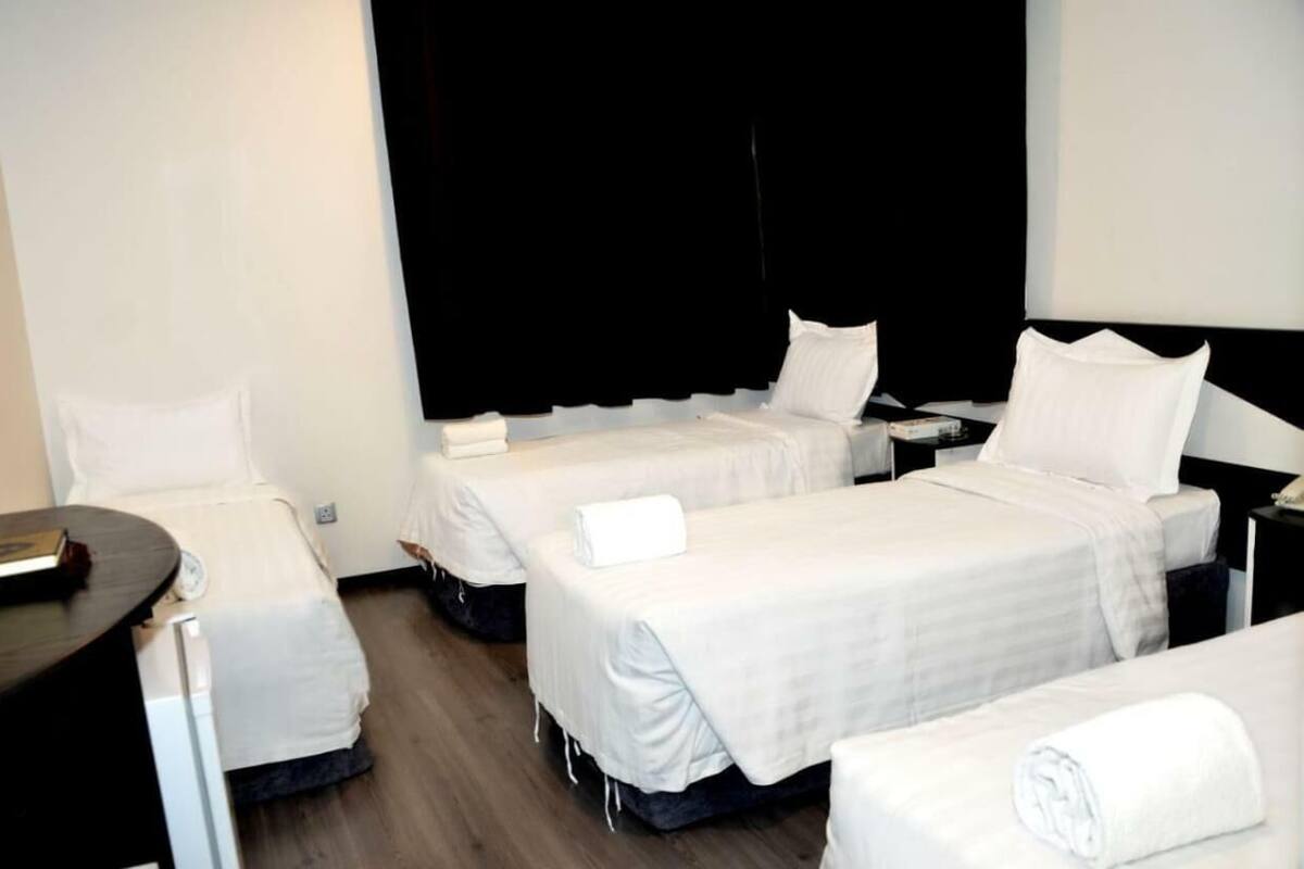 Habitación de hotel con tres camas, un escritorio y una silla.