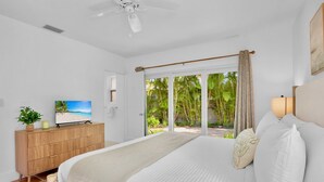 Un dormitorio con cama, televisión, cómoda de madera y vistas al exterior.