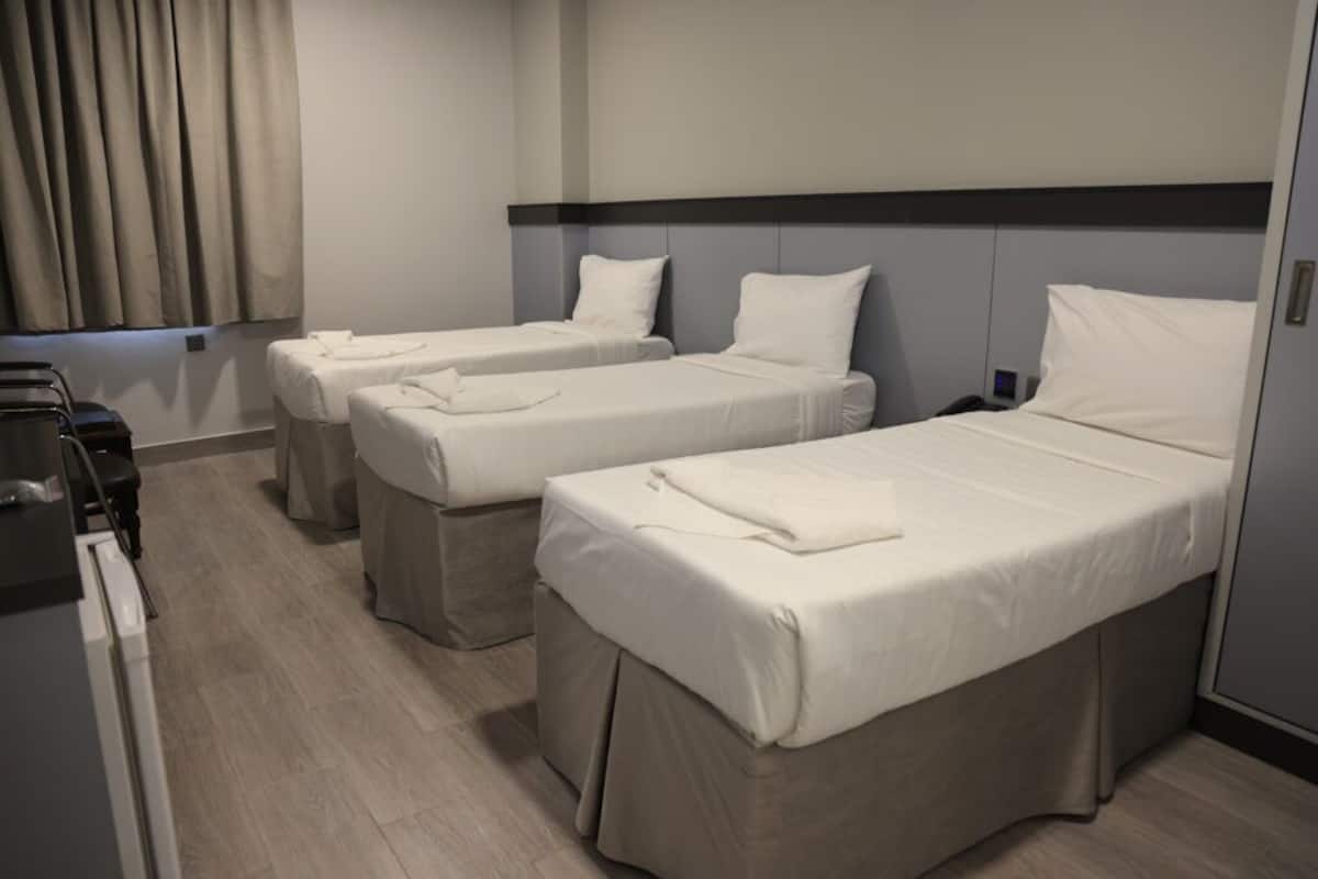 Una habitación de hotel con dos camas individuales, un escritorio pequeño y una silla.
