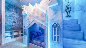 Een kinderkamer met een bed, inbouwkasten en een muurschildering.