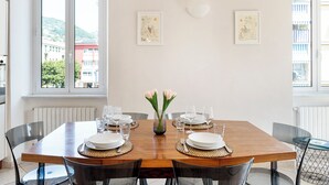 A dining table set for four with clear glass chairs, a vase with flowers, and two framed artworks on the wall. - Casa Vico delle Isole by Wonderful Italy (Recco)
