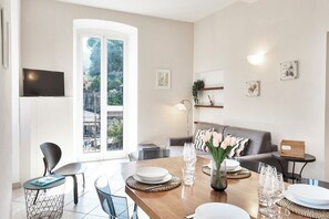 Ein modernes Wohnzimmer mit Essbereich, großen Fenstern und einem an der Wand befestigten Flachbildfernseher.