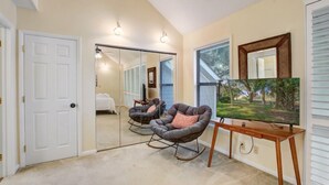 Ein Zimmer mit einem großen Spiegel, zwei Schaukelstühlen, einem Holztisch und einem Fernseher.