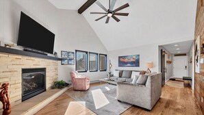 A spacious living room with a fireplace, a large flat-screen TV, a ceiling fan, and a cozy seating area. - Condo with Ski Locker | Peak Views (Breckenridge)