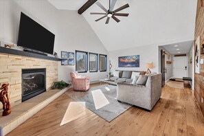 A spacious living room with a fireplace, a large flat-screen TV, a ceiling fan, and a cozy seating area. - Condo with Ski Locker | Peak Views (Breckenridge)