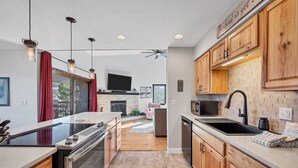 A modern kitchen with wooden cabinets, a built-in oven, and a large island with a stovetop. - Condo with Ski Locker | Peak Views (Breckenridge)