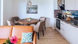Eine moderne Küche mit weißen Schränken, einem Holztisch und einer Pendelleuchte.