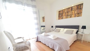 Una camera da letto ordinata con un letto grande, comodini, una sedia e una libreria.