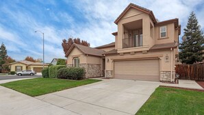 A two-story house with a garage, stone accents, and a well-maintained lawn. - Spacious 4BR/4BA Tracy Home for Families & Groups! (Tracy)
