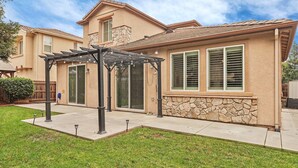 A residential house with a stone facade, a covered patio, and a well-maintained lawn. - Spacious 4BR/4BA Tracy Home for Families & Groups! (Tracy)