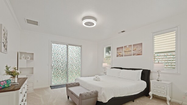 A bedroom with a large bed, a bedside table, a nightstand, a dresser, a bench, and a window with blinds. - Spacious 4BR/4BA Tracy Home for Families & Groups! (Tracy)