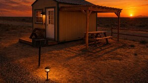 Une petite cabane en bois avec un porche, une table de pique-nique couverte et un banc.