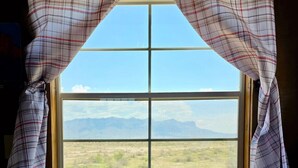 Une fenêtre donnant sur un paysage désertique et des montagnes.