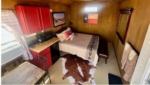 Une petite pièce comprenant un lit, un bureau et un placard rouge.