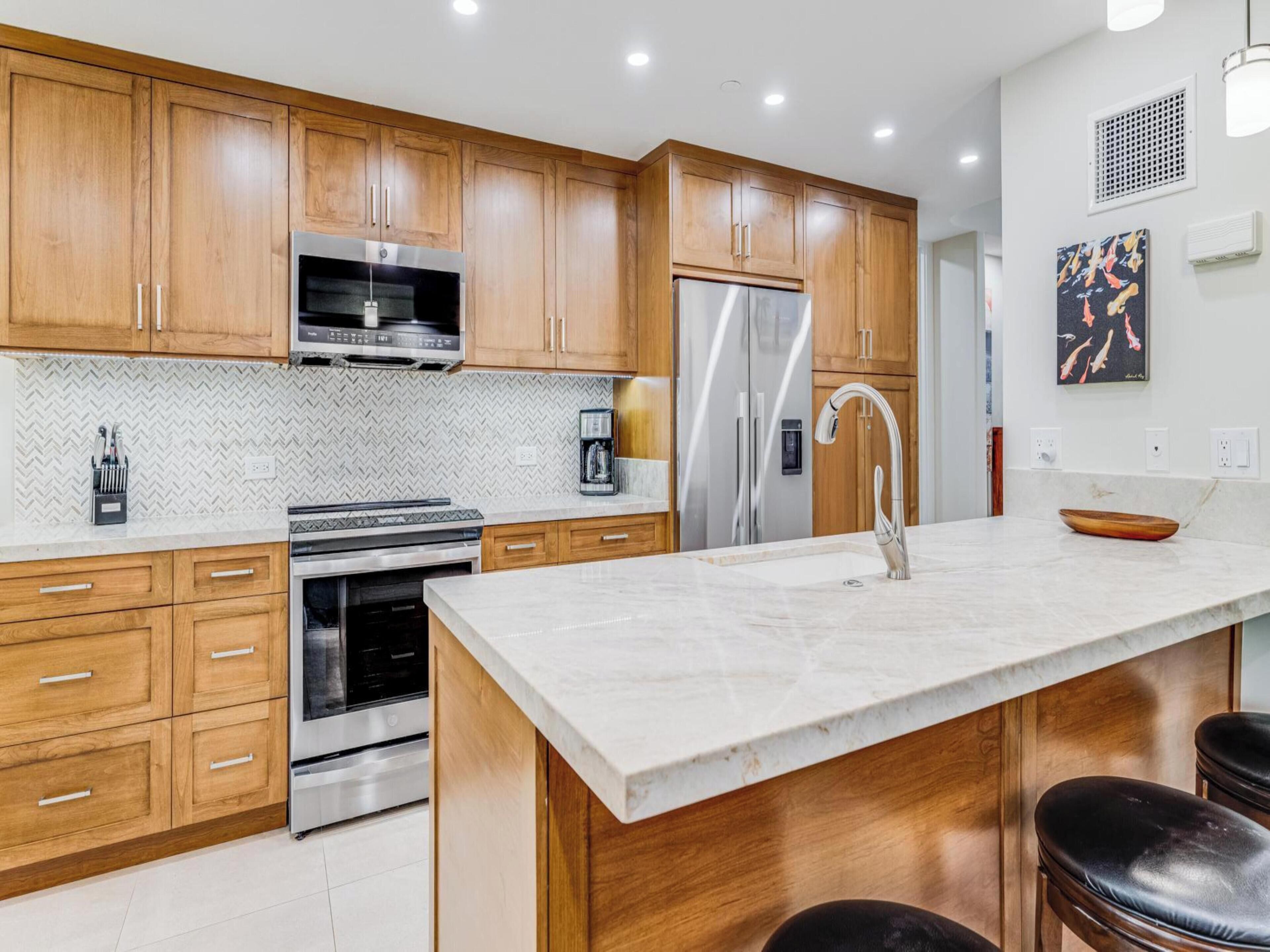 A modern kitchen with wooden cabinets, stainless steel appliances, and a marble countertop.