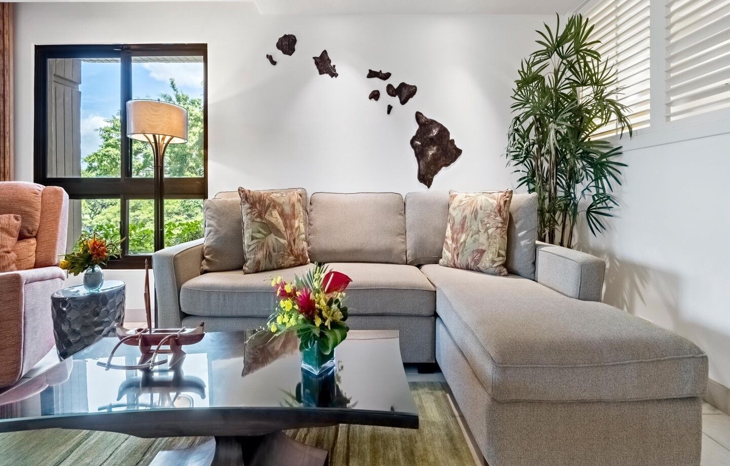 A modern living room with a sectional sofa, a glass coffee table, and decorative pillows.
