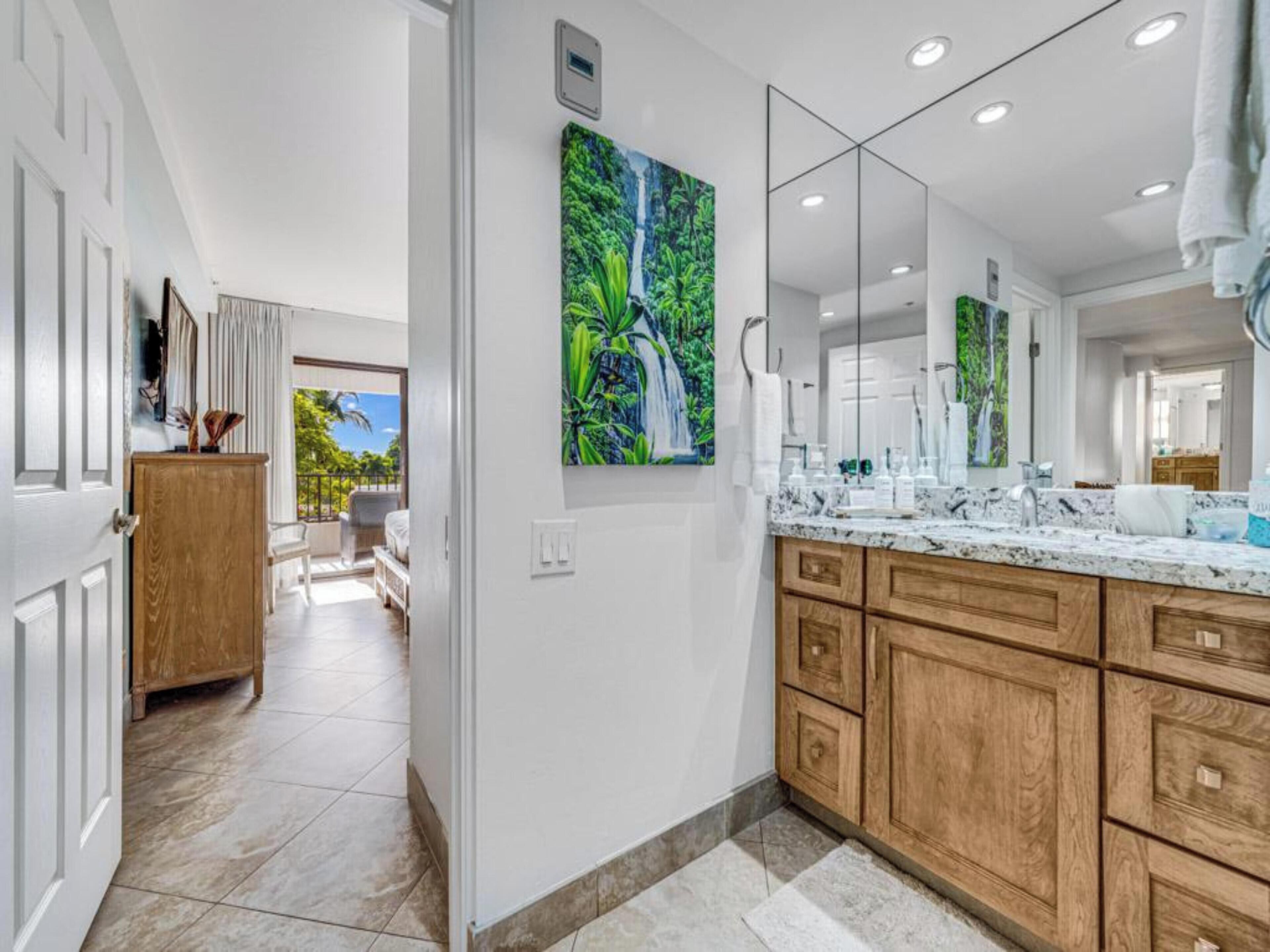 A modern bathroom with a large mirror, wooden cabinetry, and a painting of a waterfall.