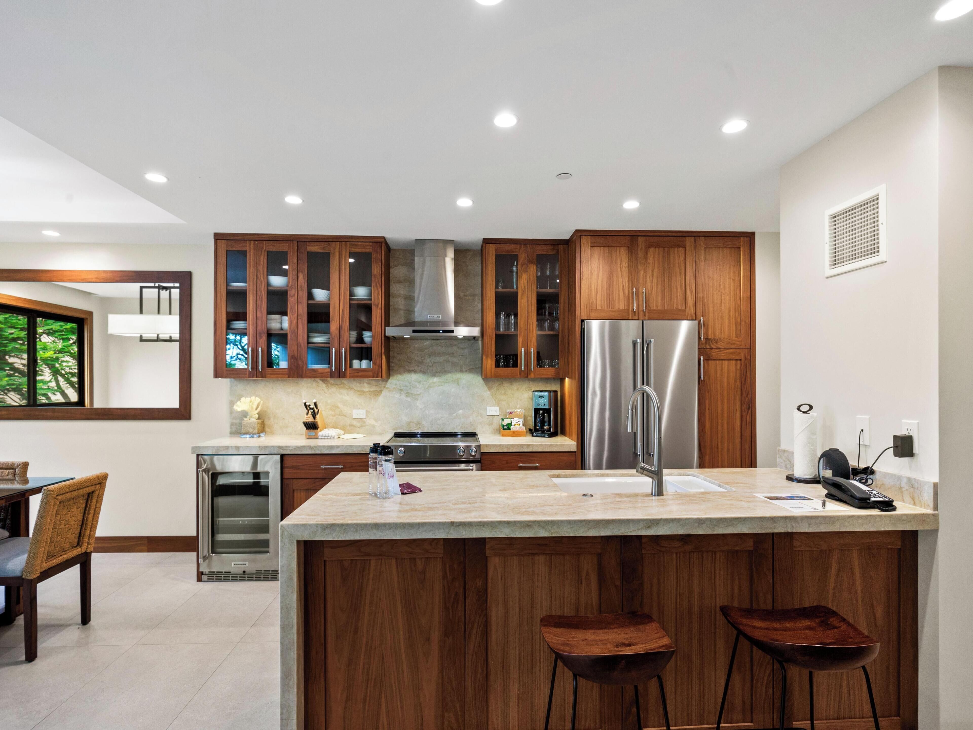 Een moderne keuken met houten kastjes, roestvrijstalen apparatuur en een groot eiland met barkrukken.