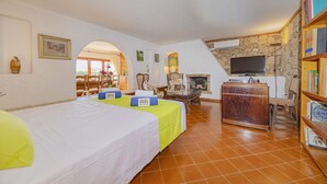 A room with two beds, a television, a fireplace, and a bookshelf. - Villa Farrutxet with sea view in Alcudia (Alcanada)