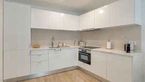 Eine moderne Küche mit weißen Schränken, einem eingebauten Backofen und einer Arbeitsfläche mit Wasserkocher und Toaster.