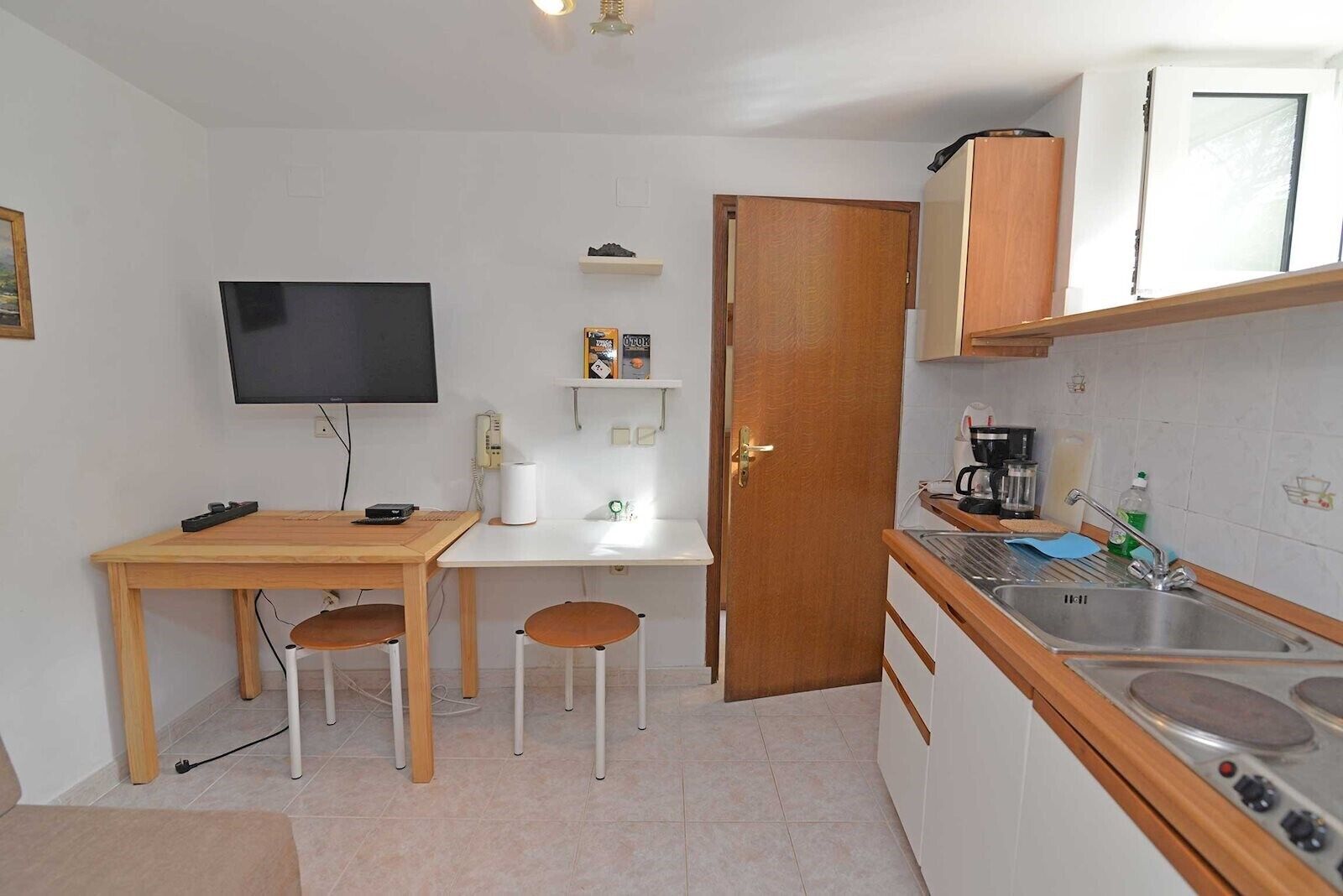 A compact kitchen with a dining area, a TV, and basic amenities.