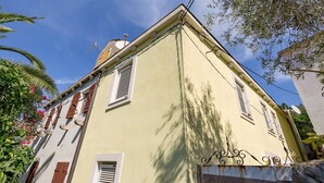 A two-story building with a light yellow facade, multiple windows with shutters, and a visible satellite dish. - Studio Veli  A in Veli Lošinj (Veli Lošinj)