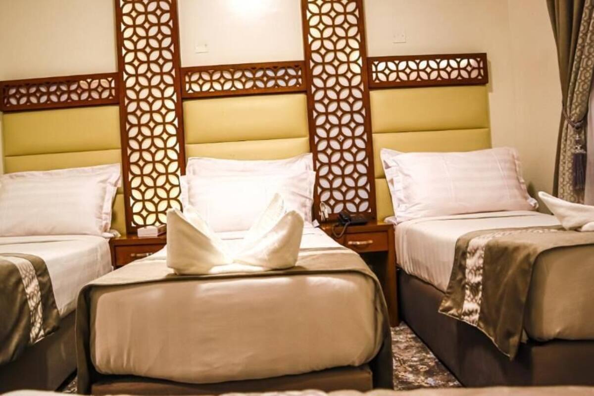 A hotel room with two beds, each with a headboard and a bedside table.