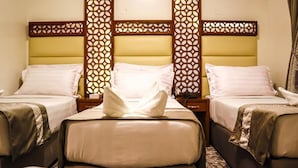 A hotel room with two beds, each with a headboard and footboard, and a decorative wooden panel on the wall. - Mukhtara Al Gharbi Hotel (Madinah)