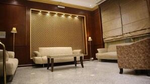 A hotel room with a beige sofa, a patterned armchair, and a decorative wall panel. - Mukhtara Al Gharbi Hotel (Madinah)