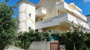 A multi-story building with balconies, a stone facade, and surrounding greenery. - 1 bedroom beautiful apartment in Omis (Omis)