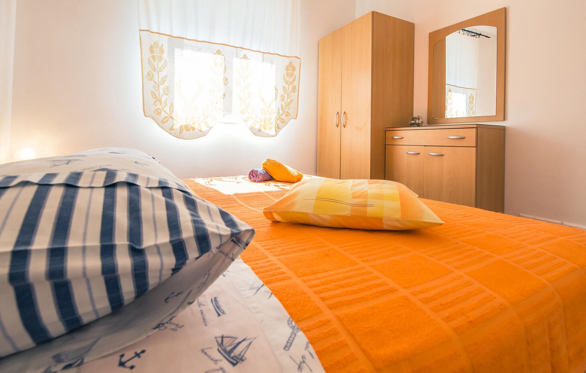 A bedroom with a bed, a wooden wardrobe, and a mirror.