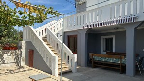 Un bâtiment doté d’un escalier menant à un balcon, d’un banc et d’une porte.