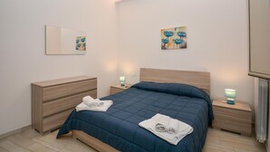 Quarto com cama, mesas de cabeceira, cômoda e quadros nas paredes.